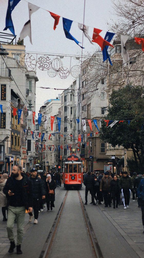 Die İstiklal Caddesi bei Tag mit roter Tram, Wimpelketten und Passanten in Wintermänteln