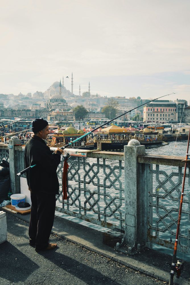 Angler auf der Galatabrücke in Istanbul, im Dunst dahinter Eminönü und die Moscheen