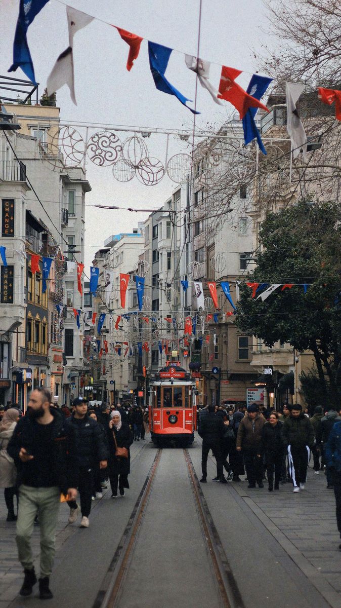 Die İstiklal Caddesi bei Tag mit roter Tram, Wimpelketten und Passanten in Wintermänteln