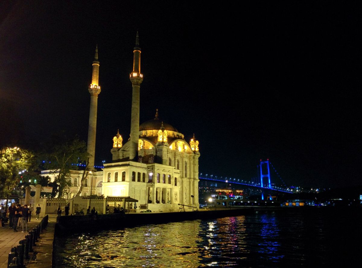Die beleuchtete Ortaköy-Moschee am Bosporus bei Nacht, dahinter die Bosporusbrücke